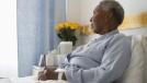 african american woman sitting in nursing home bed yellow roses on bedside table