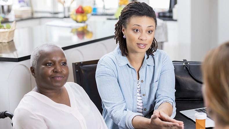 Two woman one older one younger engaged in conversation with pill bottle in foreground